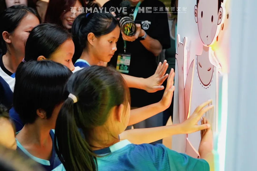 Photo of girls reaching out and touching the display panel.