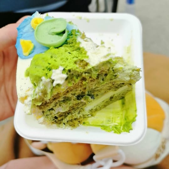 涂抹着绿色奶油、一旁放着形似水面荷叶巧克力的蛋糕。