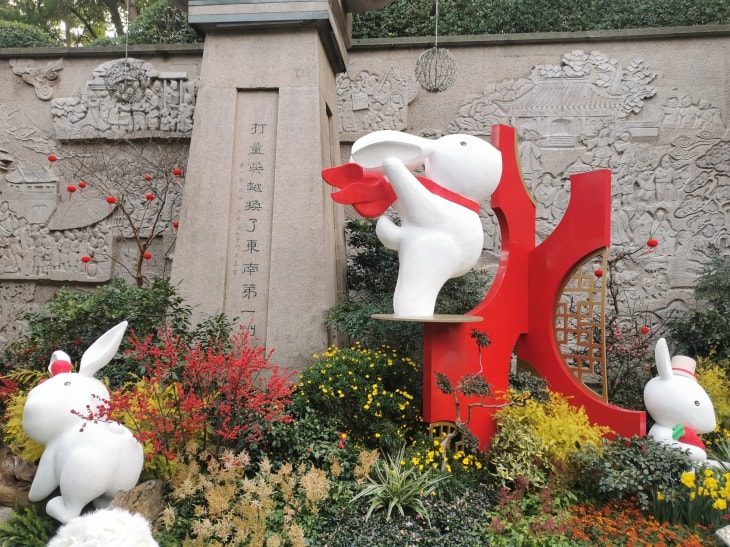 三只兔子的雕塑，中间一只作出如飞翔般的姿态，围着红色围巾，围巾背后呈翅膀形状。