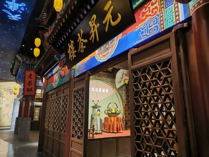 展馆中的“元昇茶楼”，里面的台上放置着两个茶壶形状的机器人，背后投影文字“乌云滚滚黑漫漫”。