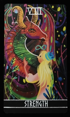 “力量”牌。一位头戴皇冠的女子抚摸着彩色丛林中的一只龙。